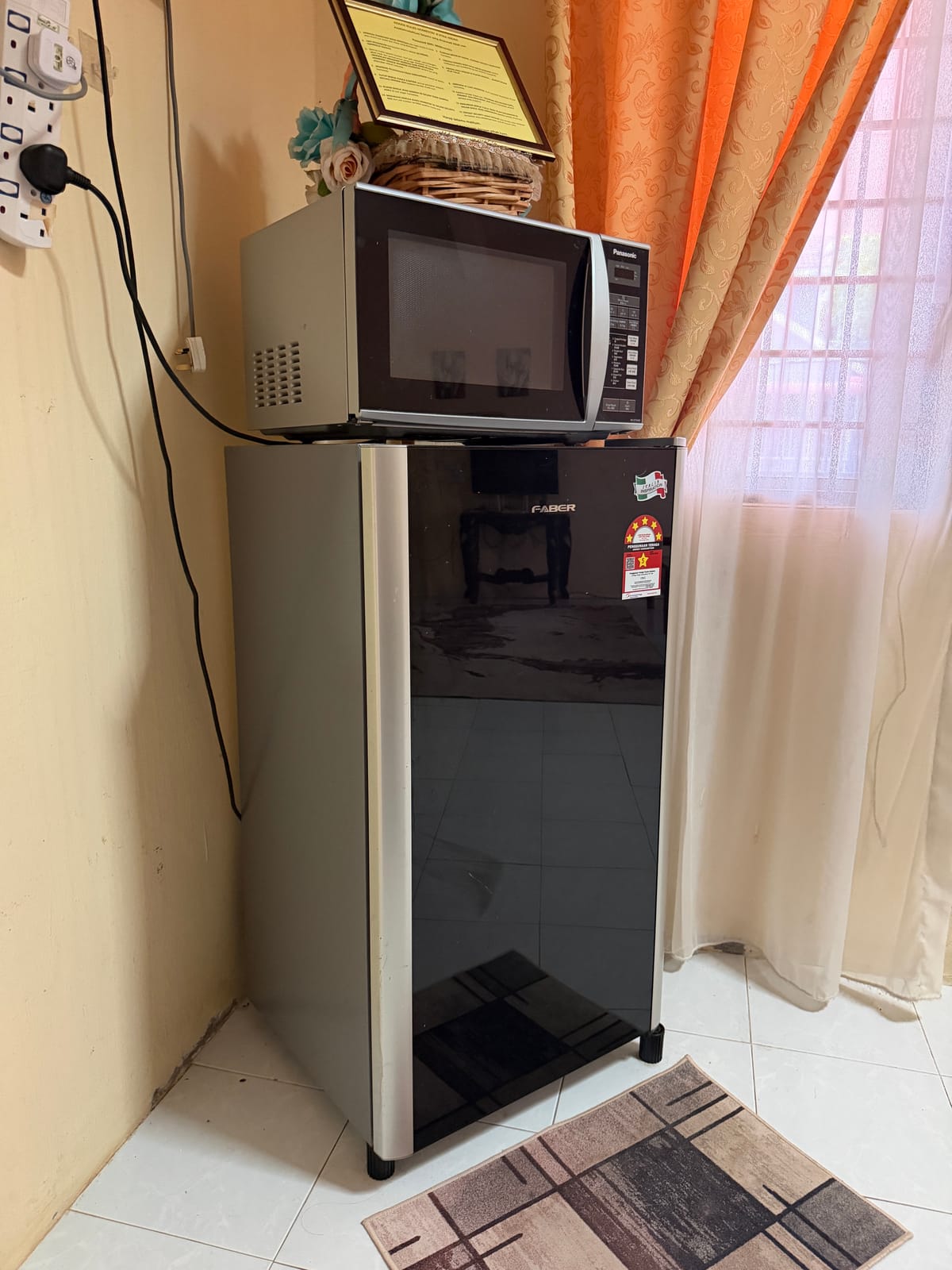 Peti sejuk dengan microwave di atasnya