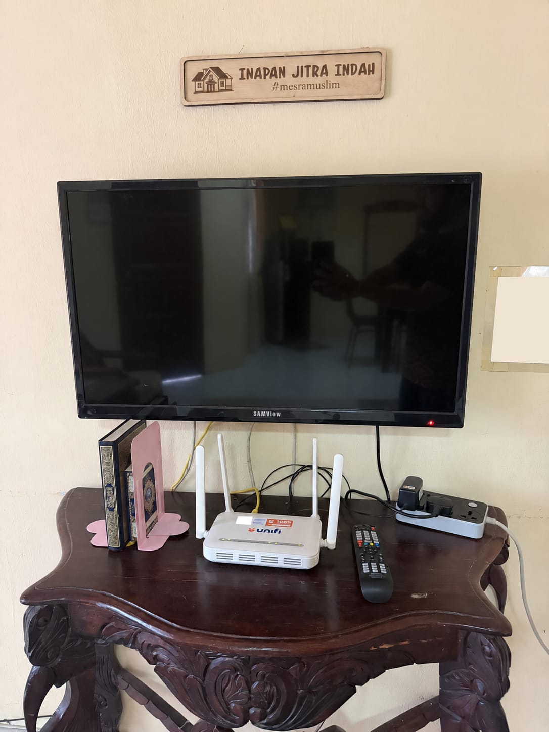 TV pada dinding dan penghala WiFi di atas meja